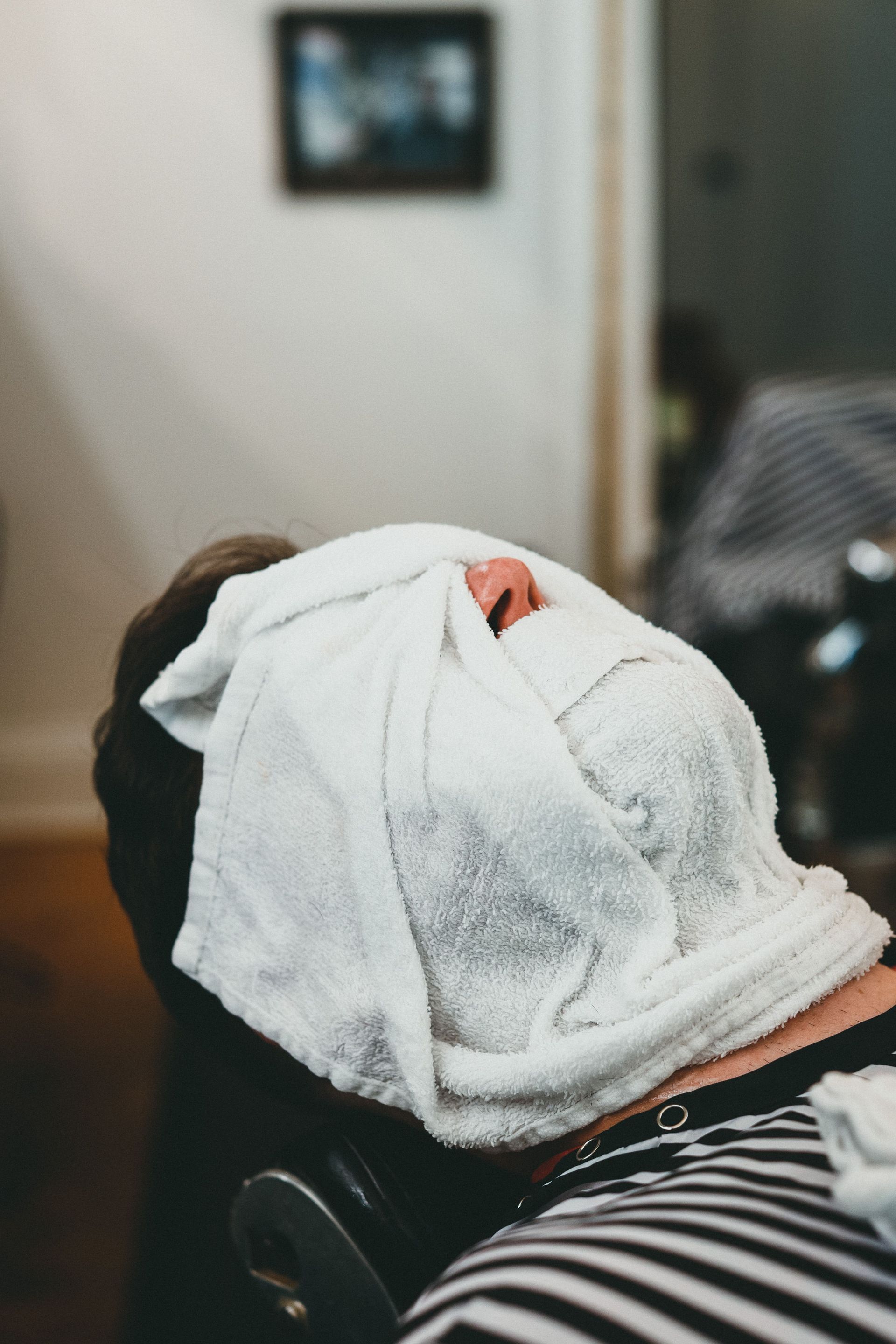 A man receives a relaxing hot towel treatment at a spa, emphasizing relaxation and self-care.